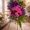 A layered standing spray of pink, purple and green that honors a
