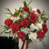Red and white roses arranged in a white hat box with a red ribbon