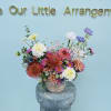 A lively, garden-style flower arrangement arranged low in a woven basket that