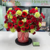 Red and lime-green floral arrangement in a pink hatbox