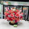 Basket arrangement of pink and coral roses with a sheer ribbon