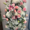 Pink roses and white lilies arranged with white hydrangeas in a standing display