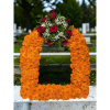 Orange marigold funeral wreath with red roses and white filler flowers
