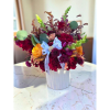 Mixed bouquet in a white ribbed vase with red, yellow, and purple flowers