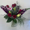Garden of Devotion is a romantic garden-inspired arrangement featuring rich red roses