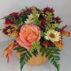 Peach rose arrangement in a pumpkin-shaped container with autumn flowers