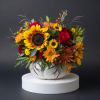 Mixed bouquet with sunflowers, red roses, and orange blooms in a white vase