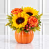 Sunflowers and orange roses arranged in a pumpkin vase