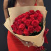 Woman holding a large bouquet of red roses wrapped in tan paper