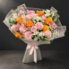 Bouquet of pink and orange roses with white flowers wrapped in translucent paper