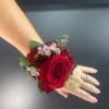 Red rose wrist corsage with small burgundy and white flowers