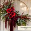 Holiday floral wreath with red blooms and a burgundy ribbon on a gold hoop