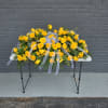 Bright yellow roses arranged in a broad, low casket spray create an