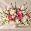 Pink and white mixed flower arrangement in a white pedestal vase