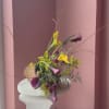 Colorful calla lily arrangement with tall branches in a woven basket