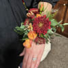 Deep burgundy chrysanthemums and bright orange roses make this wrist corsage a