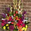 Bright pink roses and red spray roses mingle with purple chrysanthemums and