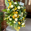 Sunny yellow roses set against crisp white carnations give this standing spray