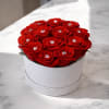 An elegant round hat box featuring perfectly arranged red roses, each accented