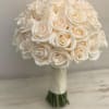 An opulent arrangement of perfectly rounded champagne-toned roses, meticulously crafted into a
