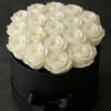 A dense cluster of pristine white roses set against a matte black