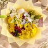 Bouquet of yellow daisies, white lilies, and red flowers wrapped in pale yellow paper