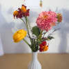 Pink, yellow, and red flowers in a white vase