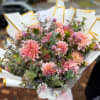 Pink dahlia bouquet wrapped in white paper with gold trim