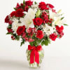 Red roses and white lilies in a glass vase with a red ribbon