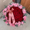 Red roses center with pink spray-rose border and white accents, wrapped in