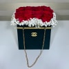 Red roses arranged in a black box with white baby's breath and gold chain handles.