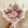 Pink chrysanthemum bouquet wrapped in white paper with a satin ribbon