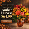 Fall bouquet in an amber vase with orange, yellow, and red flowers