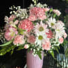 Arranged in a ribbed pink ceramic vase, the composition is rounded and