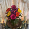 The arrangement's dense cluster of gerbera daisies-vivid pinks, purples, sunny yellows and