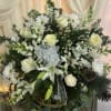 White roses and daisies arranged in a basket with a sheer ribbon