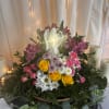 Mixed flower arrangement with roses, daisies, and an angel figurine