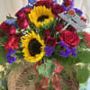 Basket arrangement with red roses, sunflowers, and purple flowers