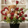 A plush teddy bear peeking out from a sea of red roses
