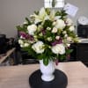 A cluster of pure white roses and calla-like white lilies meets delicate