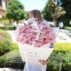 Large bouquet of pink roses wrapped in white paper