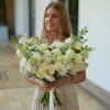 Woman holding a large white bridal bouquet with roses and round blooms