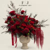 Red roses and burgundy blooms arranged in a cream pedestal vase