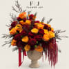 Orange and burgundy rose arrangement in a beige urn vase