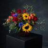 A bold garden-inspired arrangement featuring radiant sunflowers, rich red roses, fresh greenery