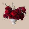 A lush cluster of deep red roses arranged in a white ribbed