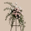A tall, cascading sympathy or celebration arrangement that reads as soft and