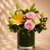 A soft and radiant floral arrangement featuring delicate pink roses, golden lilies