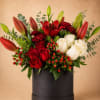Red and white roses with lilies in a black box arrangement