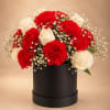 Red carnations and white roses arranged in a black hat box
